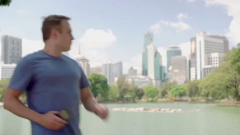 Male runner jogging in park. Fit male sport fitness training. Making photo on Stock Footage
