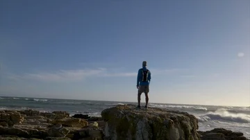 Male runner resting after jogging onto a rocky outcrop Stock Footage 85938357
