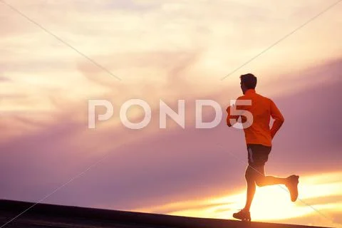 Male runner silhouette, running into sunset Stock Photos
