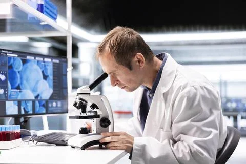Male science expert operates with microscope and laboratory tray Stock Photos