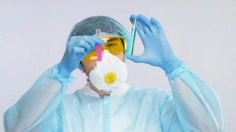 Male scientist comparing two samples of virus in test tubes wearing biohazard Stock Footage 127035863