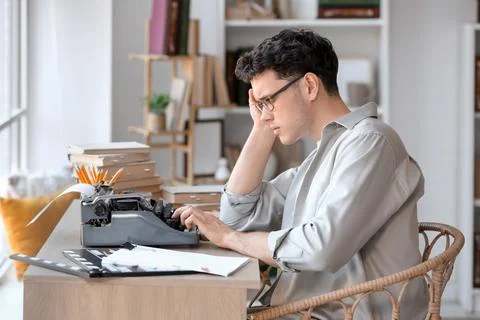 Male screenwriter using typewriter at table in office Stock Photos