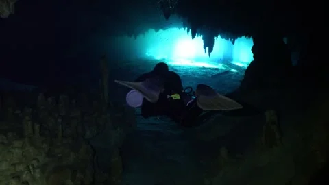 Male scuba diver with a flashlight exploring a dark underwater cave with Vídeos de archivo 331341030