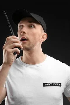 Male security guard using portable radio transmitter on dark background Stock Photos