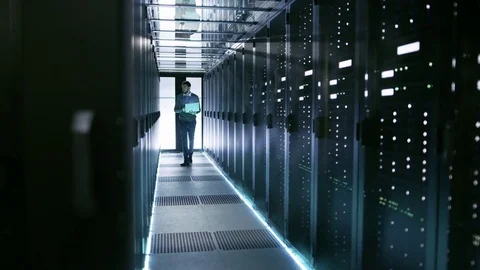 Male Server Engineer Walks with Laptop Through Working Data Center Stock Footage 73731482