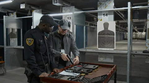 Male Shooting Instructor Demonstrating Security Officer How to Load Gun Stock Footage 305282683
