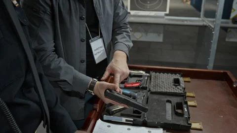 Male Shooting Instructor Demonstrating Security Officer How to Load Gun Stock Footage 305282906