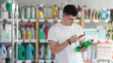 Male shopper checks a QR code on a dishwashing sponge label in a supermarket Stock Footage 326315012