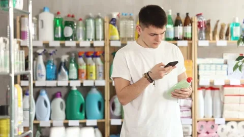 Male shopper checks a QR code on a dishwashing sponge label in a supermarket Stock Footage 342127378