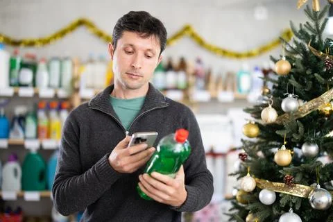 Male shopper checks QR code on a dishwashing sponge label in supermarket Stock Photos