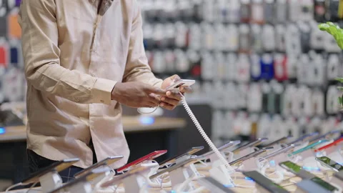 Male shopper with mask is choosing mobile phone in store, viewing exhibition Stock Footage 153132653
