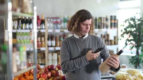Male shopper scanning QR code on bottle wine label in grocery department of Stock Footage 321329671