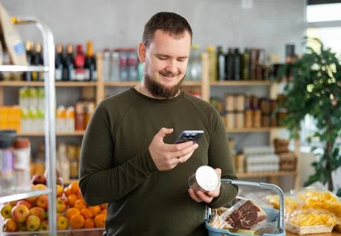 Male shopper scanning QR code on tin can label in supermarket Stock-Fotos