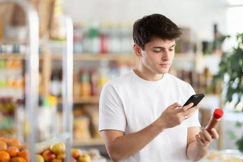 Male shopper scanning QR code on ground pepper label in grocery department of Foto stock