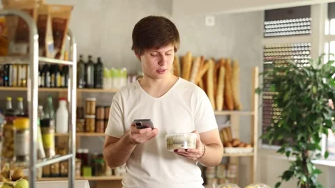Male shopper scans QR code on the label of jar of pickled herring in a Stock Footage 306981630