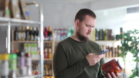 Male shopper scans a QR code on a label of canned tomatos in a supermarket Stock Footage 330384401