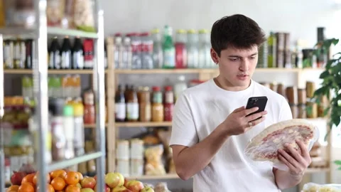 Male shopper scans QR code on frozen prosciutto pizza with smartphone Stock Footage 347258347
