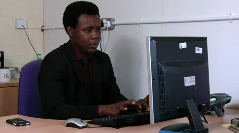 Male sits at computer comparing paperwork to screen data Stock Footage 30444041