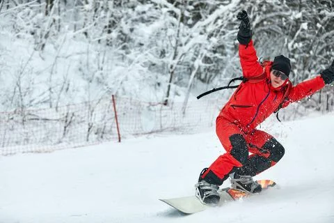 Male snowboarder in a red suit rides on the snowy hill with snowboard, Skiing Stock Photos