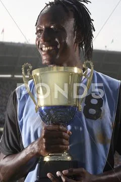 Male soccer player proudly holding trophy Stock Photos