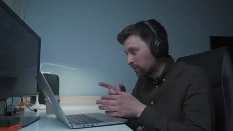 A male software developer makes a videocall with coworkers while sitting at his 動画素材 199116260