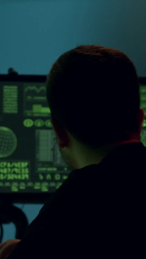 Male software developer working on a computer at a modern desk, illuminated by Stock Footage 313927895