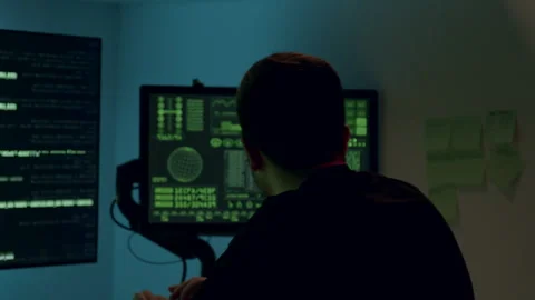 Male software developer working on a computer at a modern desk, illuminated by Stock Footage 315442422