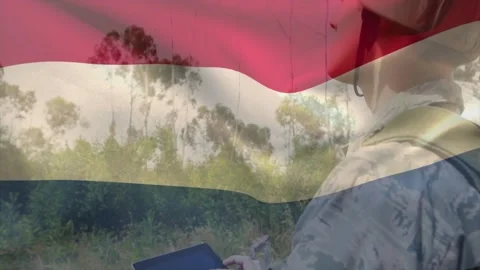 Male soldier tapping tablet, securing chin strap while scanning treeline for Stock Footage 329899293