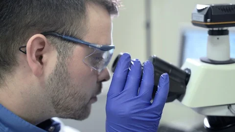 Male specialist is using microscope during working day in pharmaceutical Stock Footage 128296535