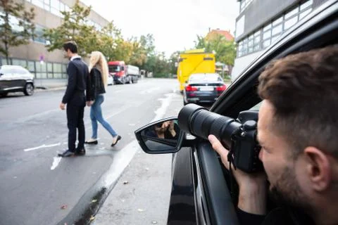 Male Spy Taking Photograph Of A Couple Walking On Street Stock Photos