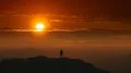 The male standing on a mountain top on a sunrise background. time lapse 4k or 4k+ Resolution