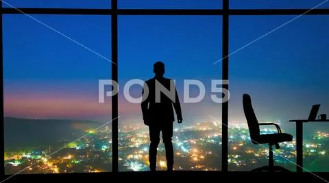 The male standing near the window on a night city background Stock Photos