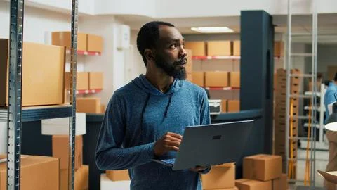 Male storage room worker using laptop to write products data Stock Photos