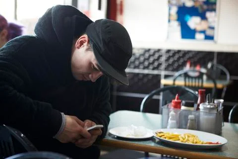 Male Student In Cafe Checking Message On Mobile Phone Stock Photos