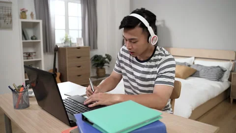 Male student with headset is writing notes Stock Footage 197367780