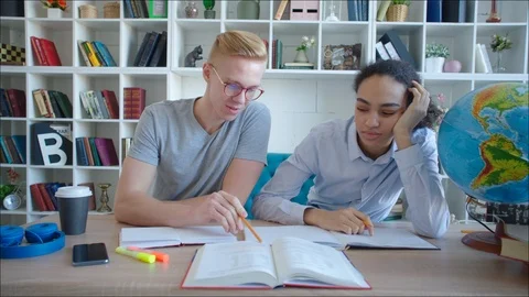 Male student helping african caucasian female student to read up for exam in the Stock Footage 104430053