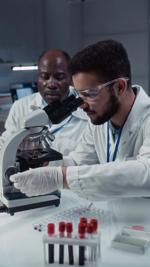 Male Student Learning to Use Electronic Microscope in Lab with Professor Stock Footage 312377815