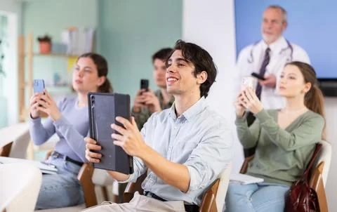 Male student scanning qr code in lecture hall Stock Photos