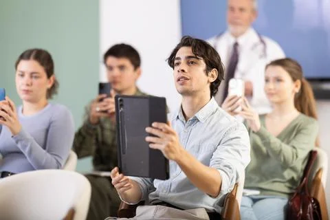 Male student scanning qr code in lecture hall Stock Photos