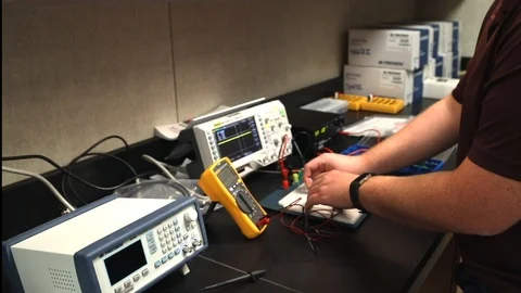 Male student at school testing electrical equipment with multimeter in Stock Footage 123322432