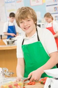 Male student slicing berries in cooking class Stock Photos