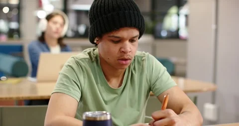 Male student studying, writing notes with orange pen at table, noting woman Stock Footage 340257209