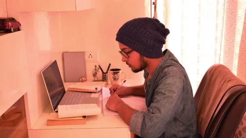 Male student taking writing notes notebook laptop doing homework drinking coffee Stock Footage 130732823