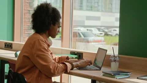 Male Student Typing on Laptop while Sitting by Window in Modern Library Stock Footage 342121522