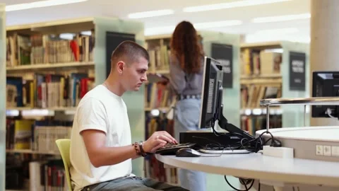 Male student works at computer in library Stock Footage 315548340