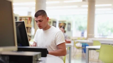 Male student works at computer in library Stock Footage 326307827