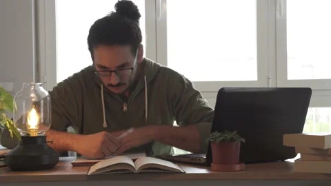 Male studying and taking notes with laptop and books Stock Footage 162107332