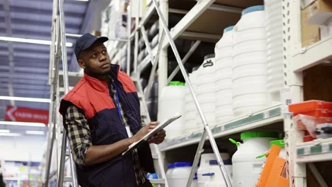 Male supervisor examining goods on shelves with tablet using ladder Stock Footage 171657053