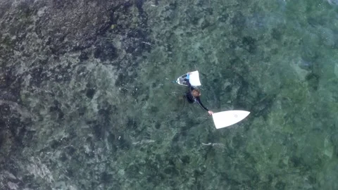 Male surfer exiting rocky patch at Balangan Beach with his broken board in Stock Footage 138536498