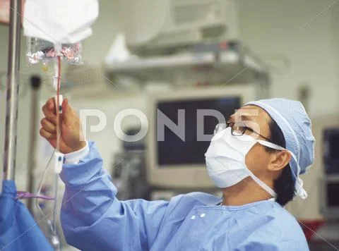 Male surgeon checking intravenous drip Stock Photos